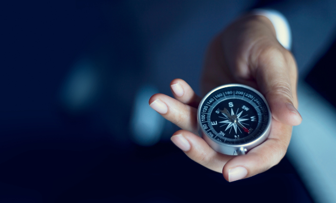 A hand holding a compass