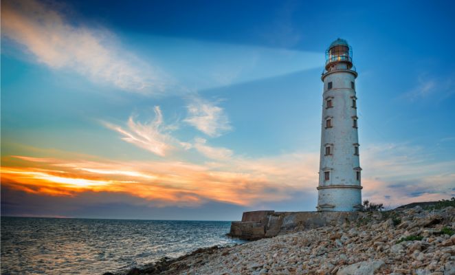 Lighthouse at dawn beaming out across the sea.