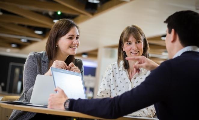 Three people in a meeting, smiling and gesticulating.