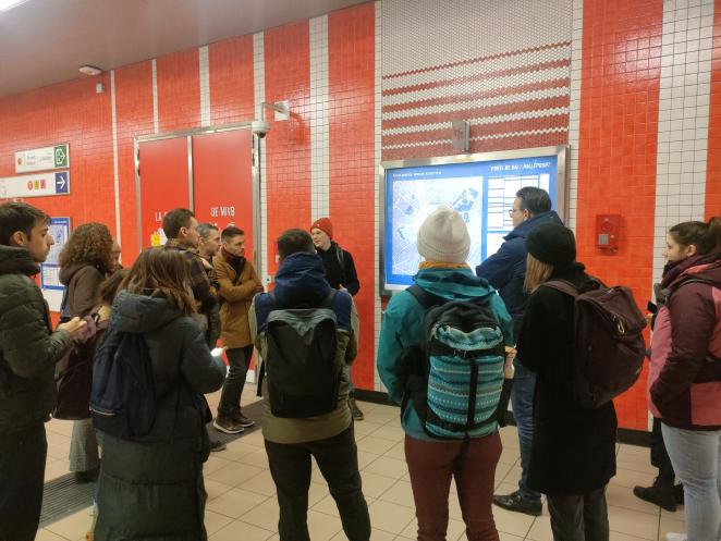 Picture of the visit at Porte de Hal. People looking at the map provided at the metro station.