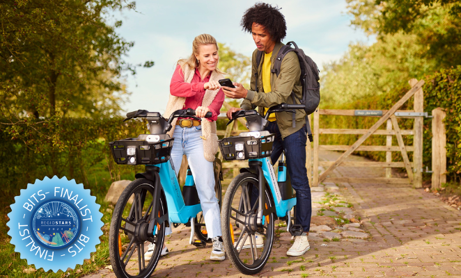 Two people with bikes checking an app in a green area in sunny weather.