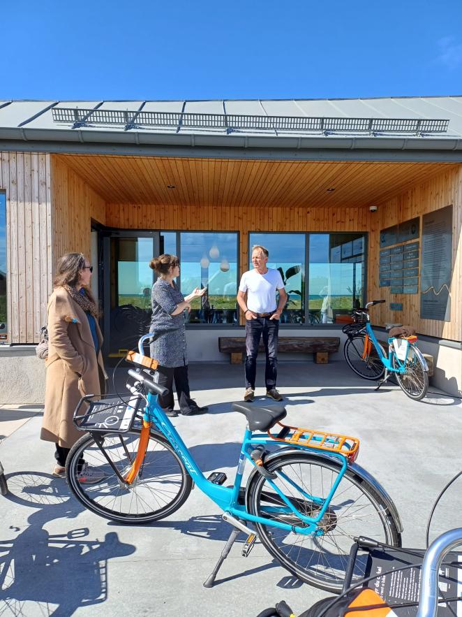 Three people are pictured during a site meeting. A bike is at the front of the picture.