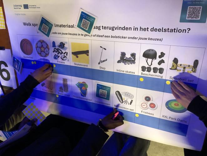Photo of hands pointing at pictures of different sports equipment options for the sharing station