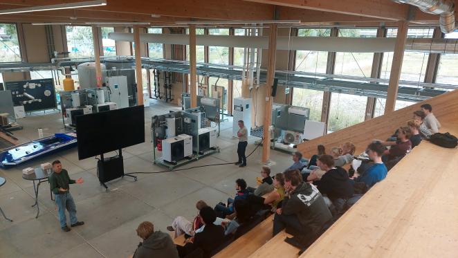 group of students look from a big wooden staircase at a presentation