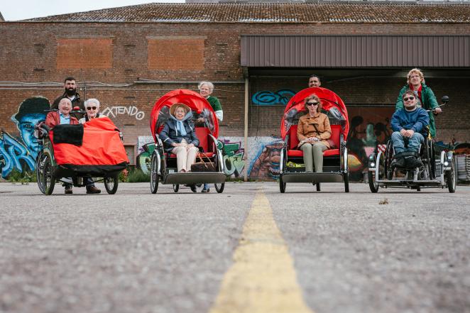 Four drivers are shown driving passengers with adapted wheeled vehicles