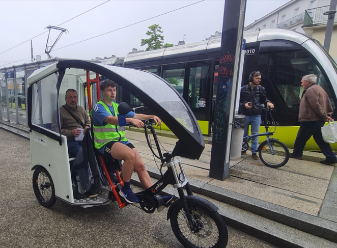 A volunteer drives a rickshaw with a passenger