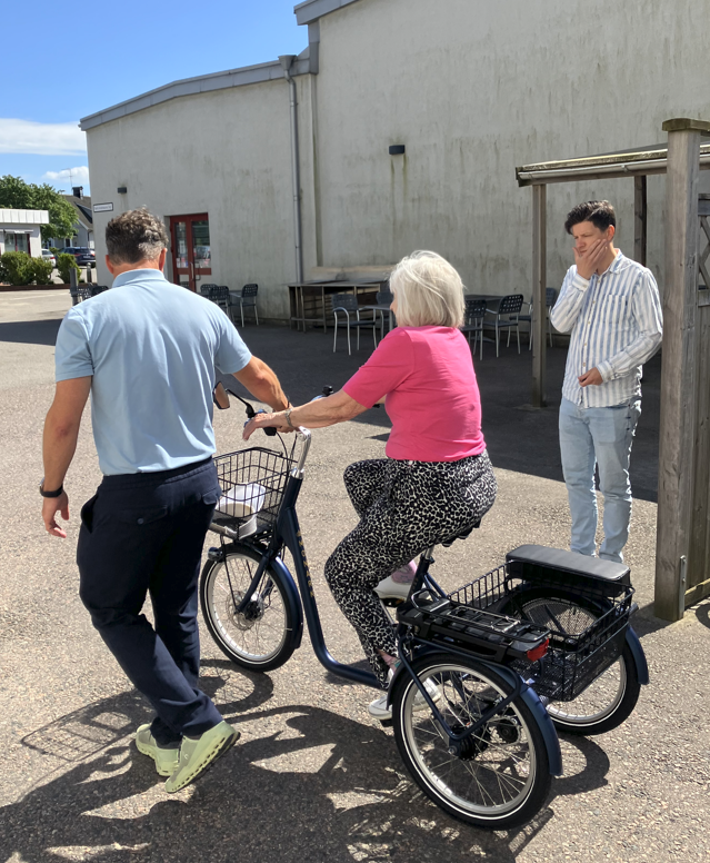 An operator helps a woman use an adapted trycicle 