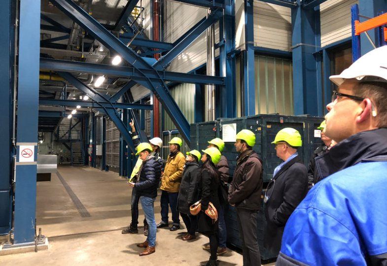 A group of people wearing helmets standing in line within a large industrial space