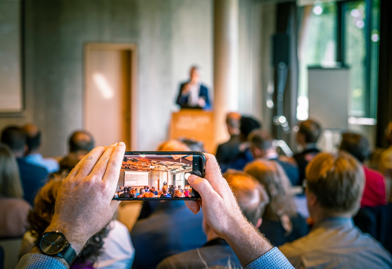Event with a speaker and a person filming with their mobile phone