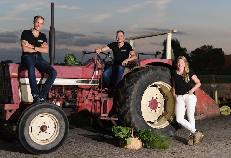 Three young people leaning on a red tractor.