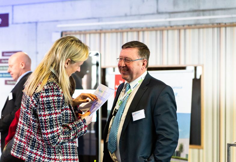 A man and a woman having a conversation in a conference lobby