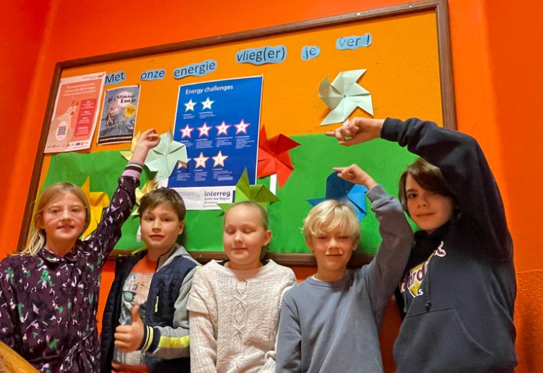 Group of school kids pointing towards an illustration on an orange wall