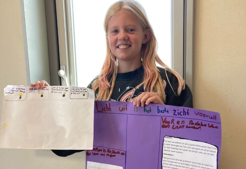 Smiling school girl holding large sheets of paper with notes on them