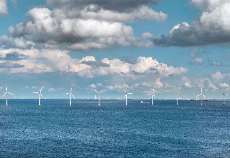 A ship sailing over the ocean between windmills