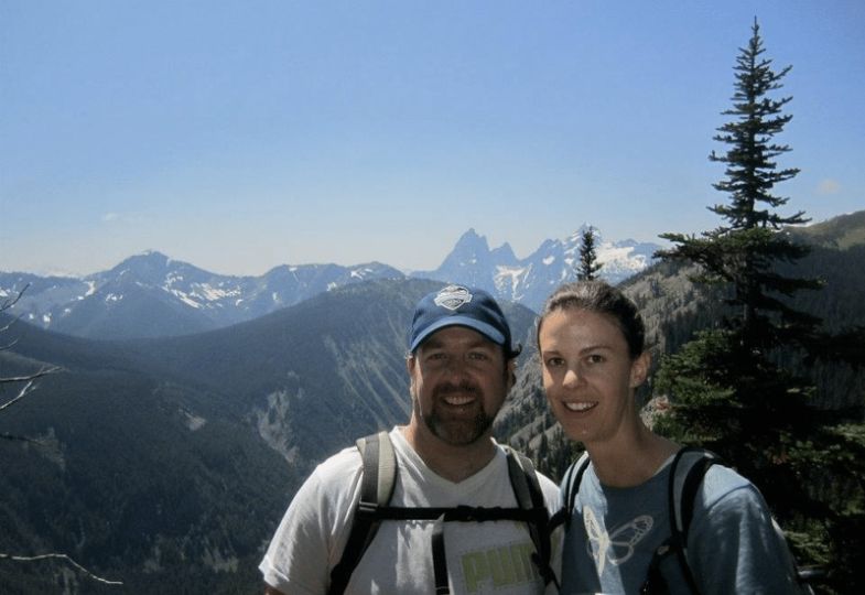 Shane and his wife in front of a mountaineous ridge and a clear blue sky