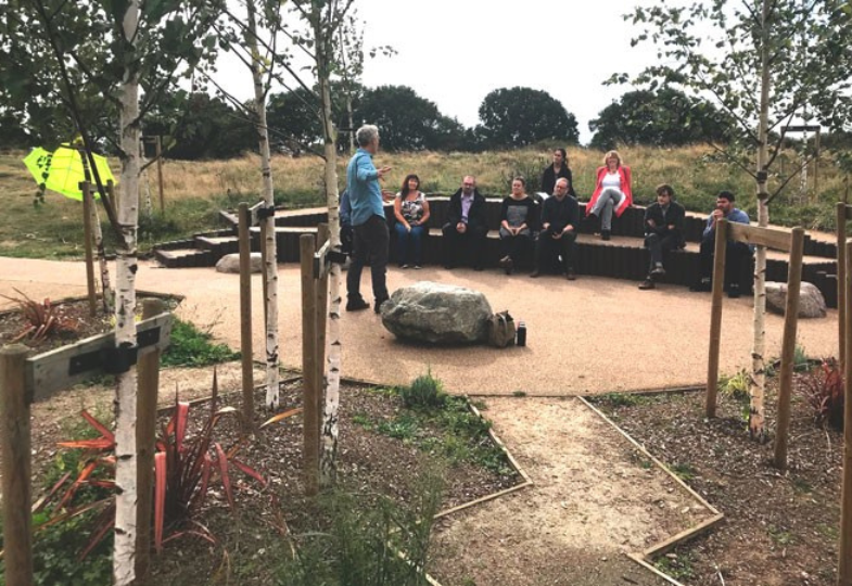 People on round bench listening to a speaker