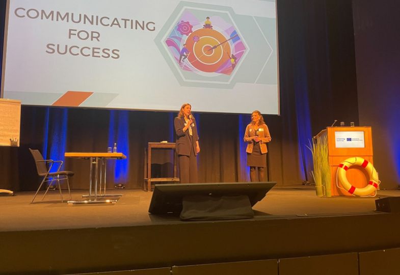 Two people in front of a big screen stating "Communicating for success"
