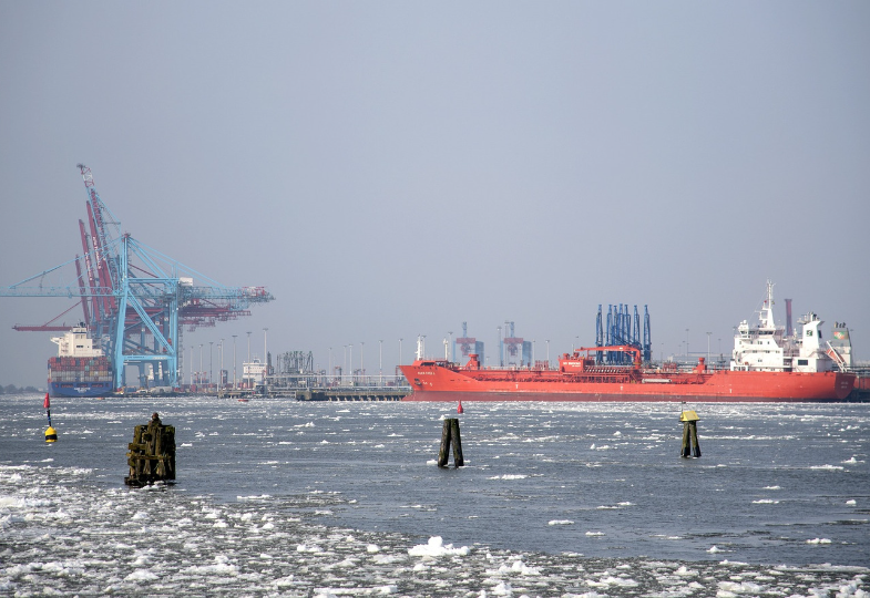 Port with cranes, a container ship and a large ship.