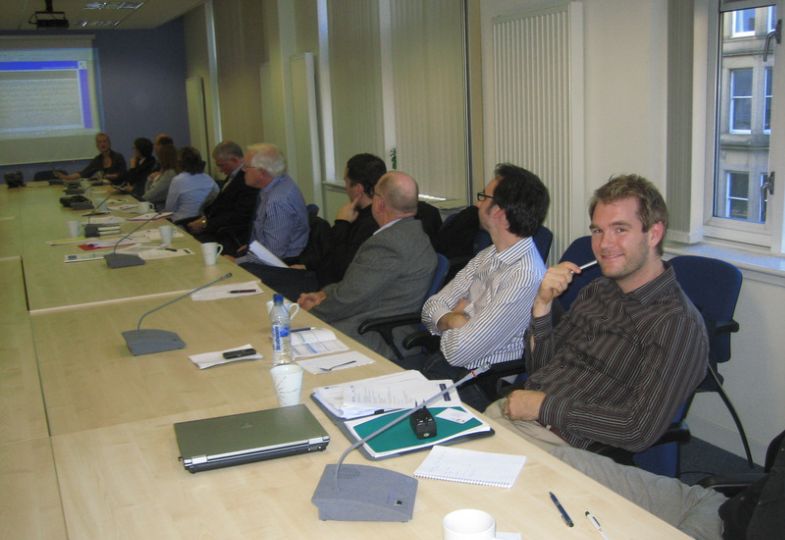 People in a meeting, sitting at a long table.