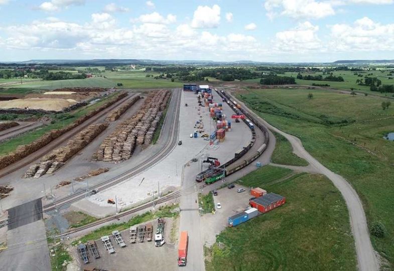 Aerial photo of the timber terminal at Skaraborg, surrounded by green landscape on a bright day with light clouds.