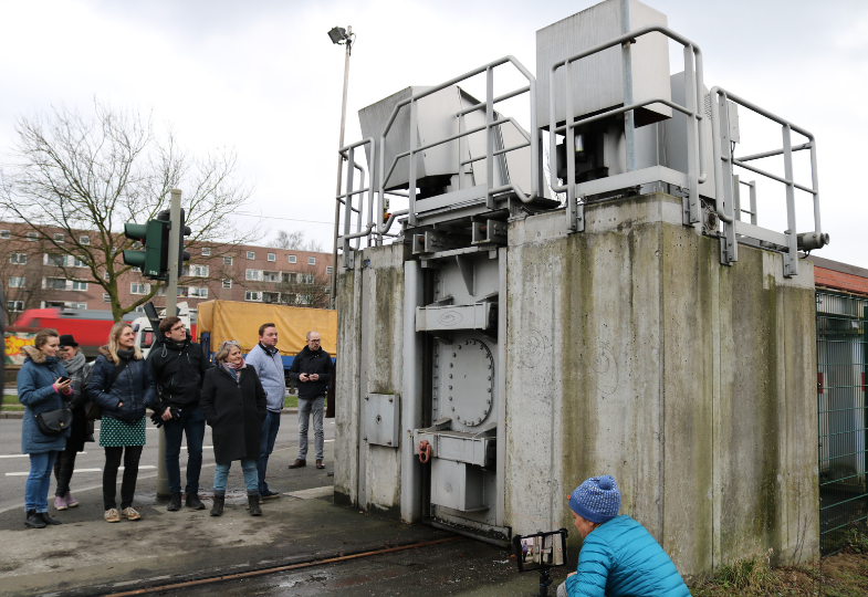 A group of people looking at an older sluice built in concrete.