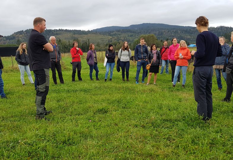A group of farmers on a field visit in Norway, with mountains in the background.