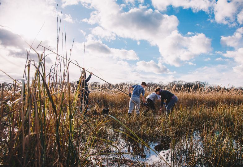 Three people taking core samples from a peatland in clement weather.