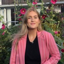 Portrait photo of the author Ida Tiverman in front of hollyhocks