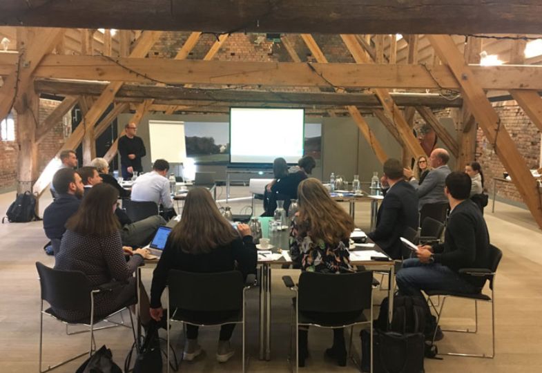 A group of people in a rustic meeting room with wooden beams.