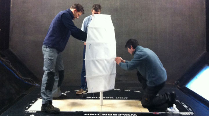 Three people working on a modern rotor sail.