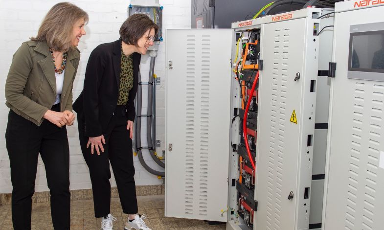 Two women looking at electricity cables in cabinets.