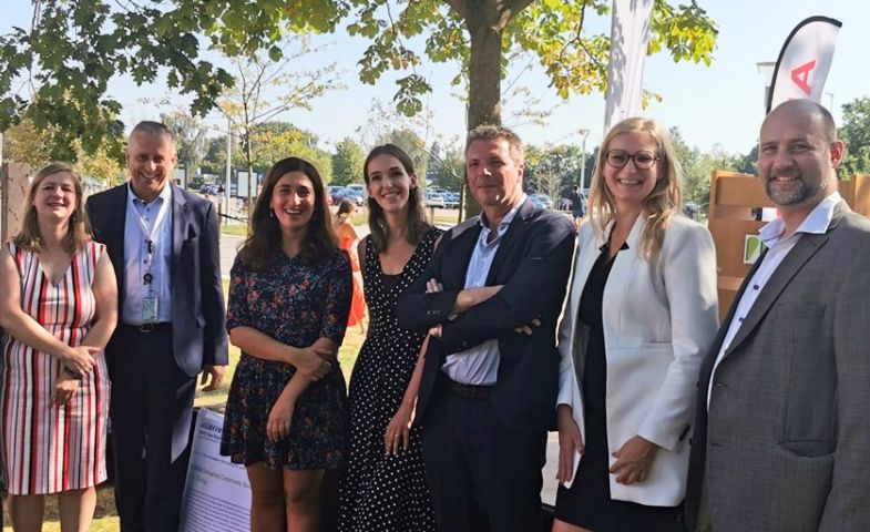 A group of people standing outdoors, smiling at the camera