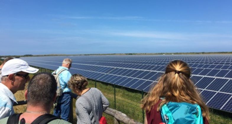 A group of people visiting a solar park in beautiful weather.