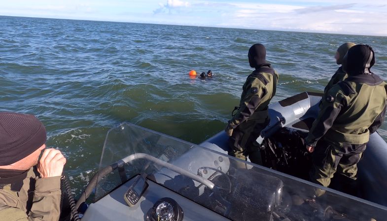 Three divers in a rubberboat on the sea.