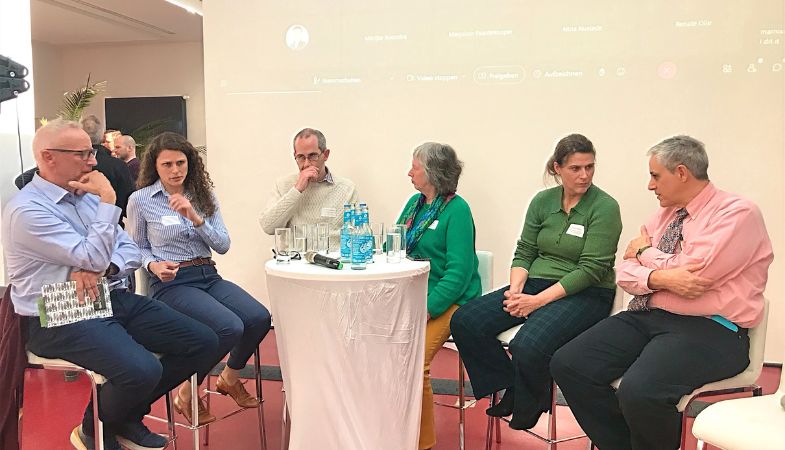 A group of six panelists seated around a small round table.