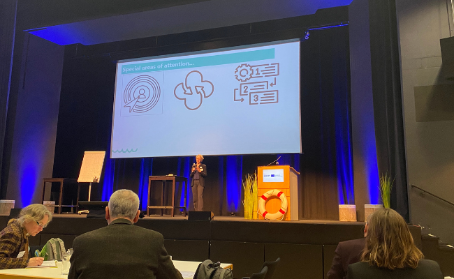 A lady on stage presenting to an audience.