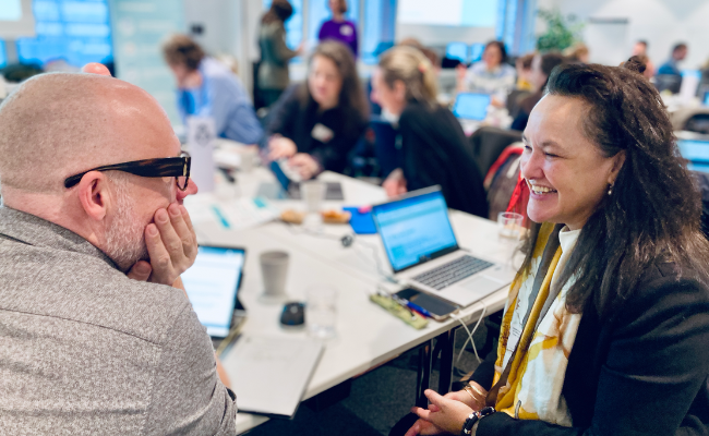 Two people in deep conversation in a room full of people.