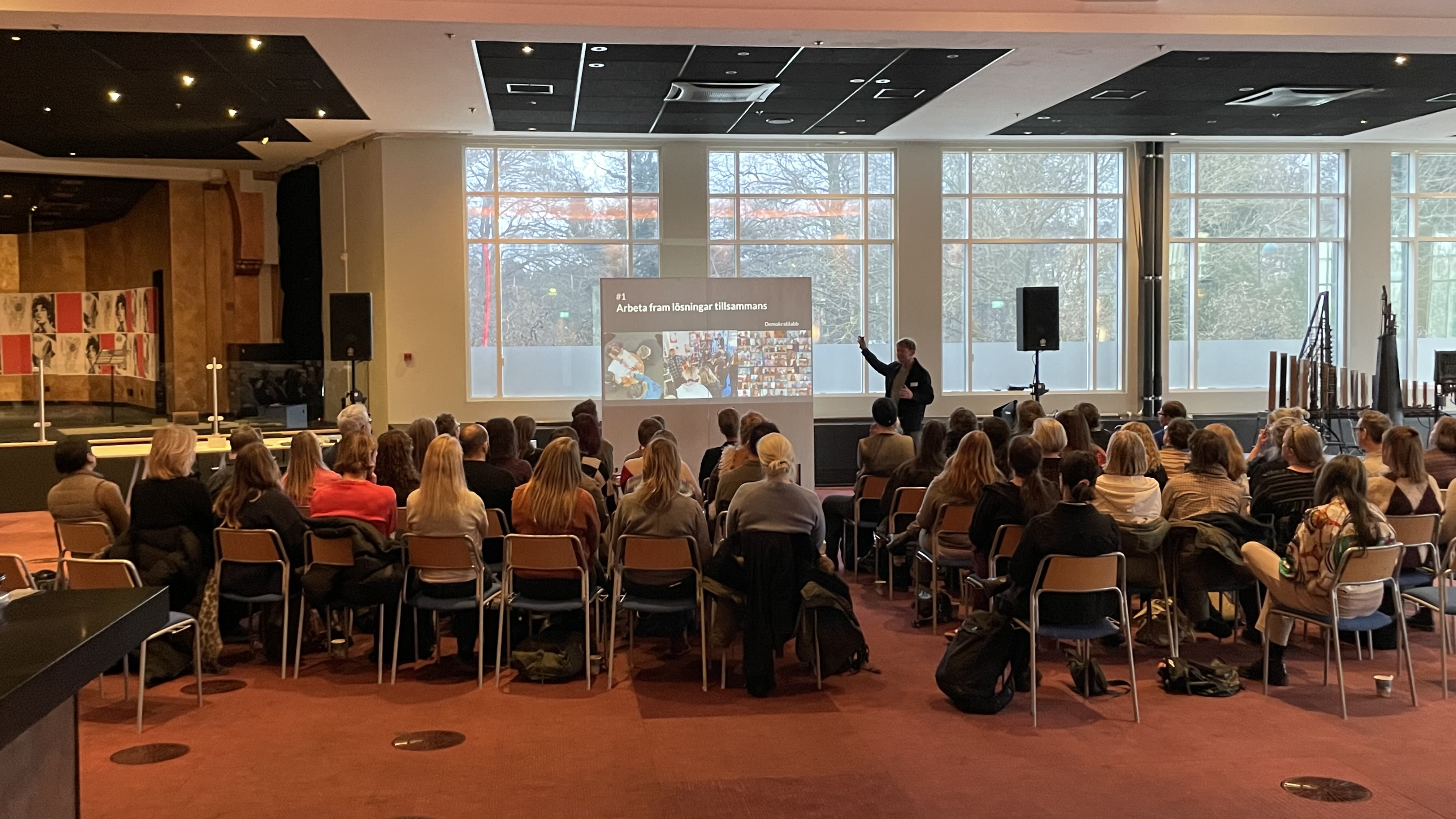 A room full of people are watching a person present about participation.
