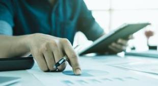 Person holding a tablet and checking documents.