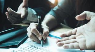 Hands gesticulating and one person holding a pen, signing a document. 