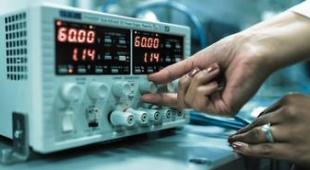 Hand turning a knob on a laboratory monitoring device.