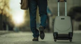 Man pulling his suitcase along a street.