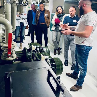 Expert explaining workings of pump station to small audience.