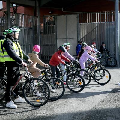 Children are shown on bikes. They're in front of a school