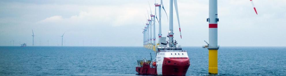 A boat and wind turbines at sea in cloudy weather.