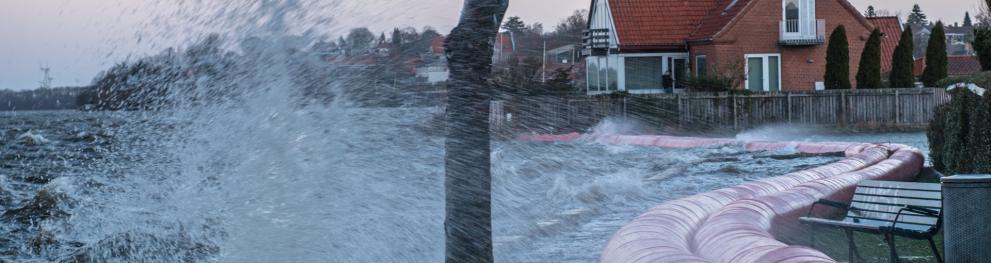 Unruly water splashing over barriers protecting a city.