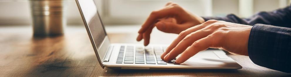 Close-up of hands using a laptop.