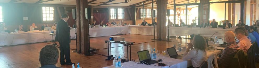 The Monitoring Committee members seated in a large room.