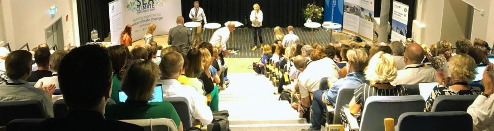 People seated auditorium style during a presentation at the North Sea Conference.