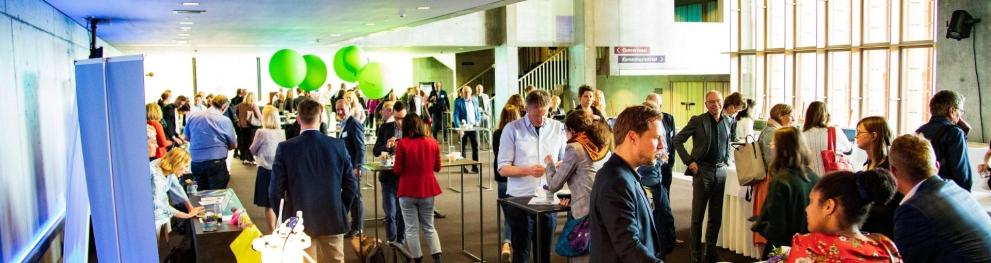 Many people standing in a lobby with posters along the walls.